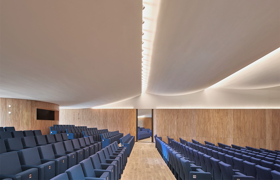 View of the auditorium, featuring tiered seating and warm wooden accents designed for optimal acoustics and comfort.